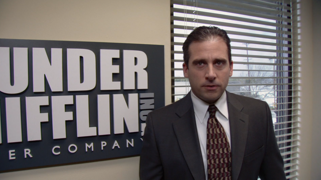 Screenshot of the Pilot episode with Michael Scott in front of the Dunder Mifflin sign